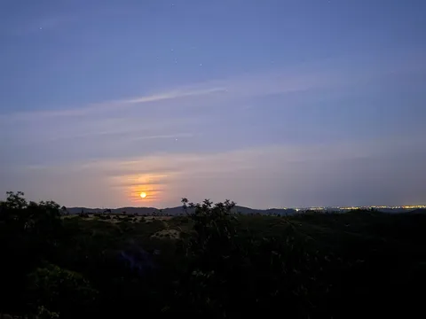 Moonrise over the hills at dusk, with distant town lights