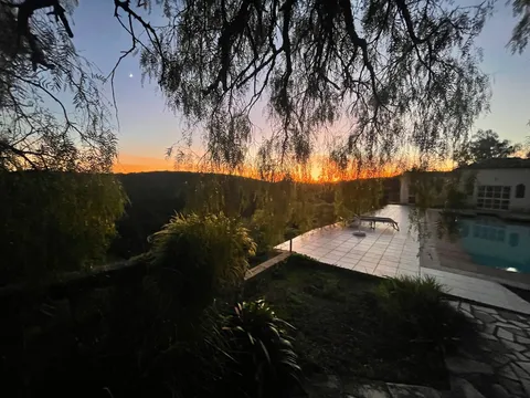 Sunset over the pool terrace, seen through hanging branches, with the Monchique hills beyond