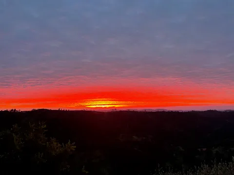 A vivid red and orange sunset over the hills