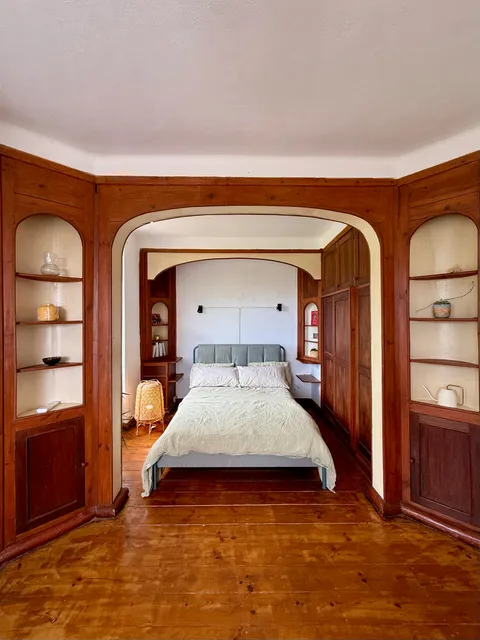 Bedroom with a wood-panelled arched alcove, bed, and built-in shelving