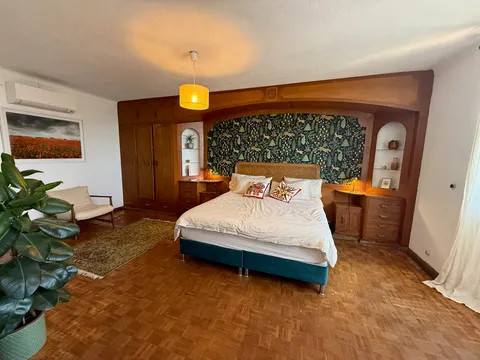 Primary bedroom with a patterned headboard wall, built-in wardrobes and shelving
