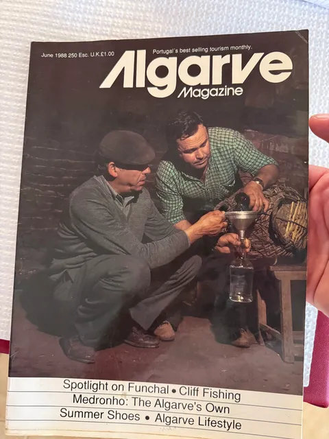 Cover of Algarve Magazine, June 1988, showing two men filtering medronho through a funnel into a bottle at a stillhouse